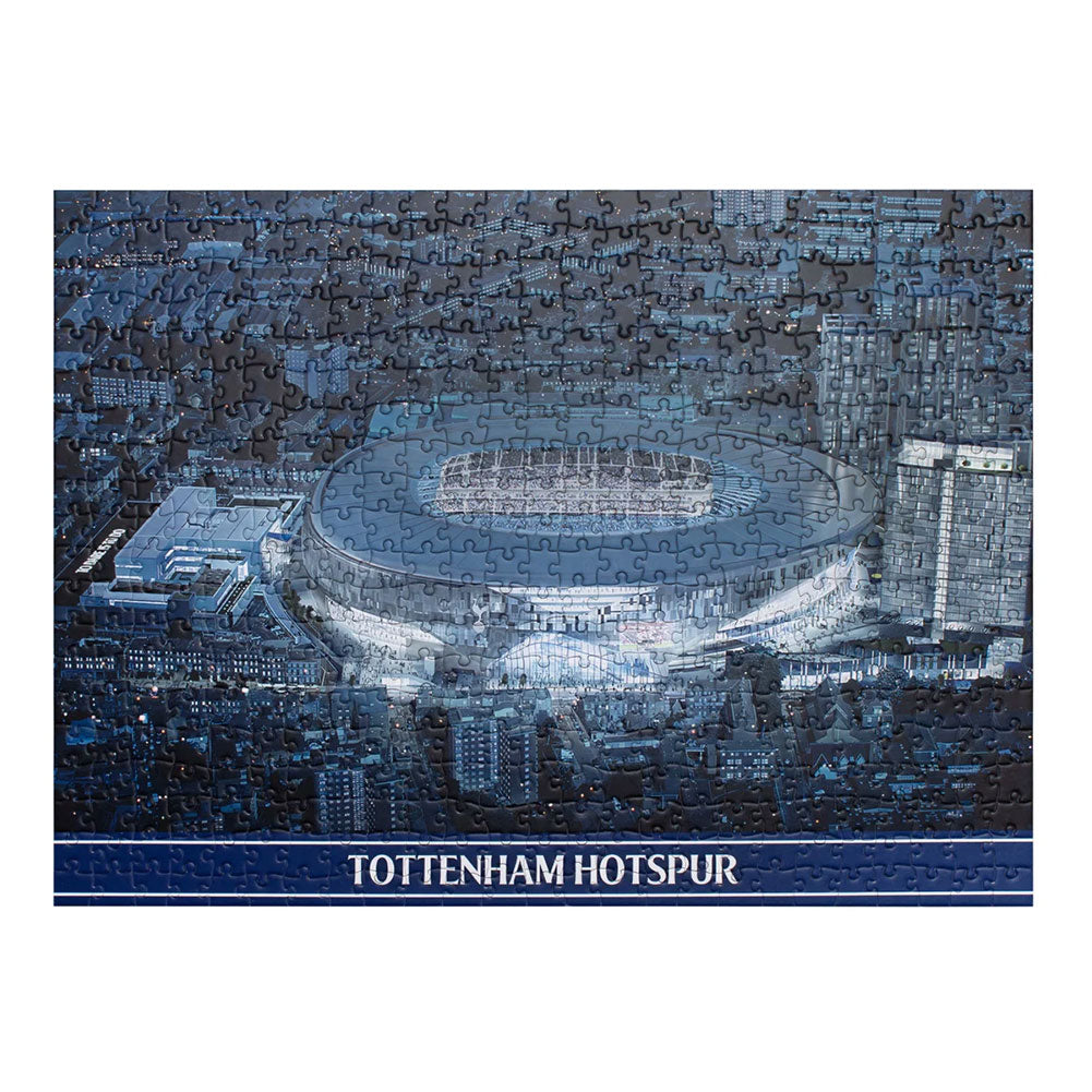 A completed jigsaw puzzle featuring a blue-toned aerial view of the Tottenham Hotspur stadium, with the text 'TOTTENHAM HOTSPUR' on a dark blue banner at the bottom, shown against a white background.